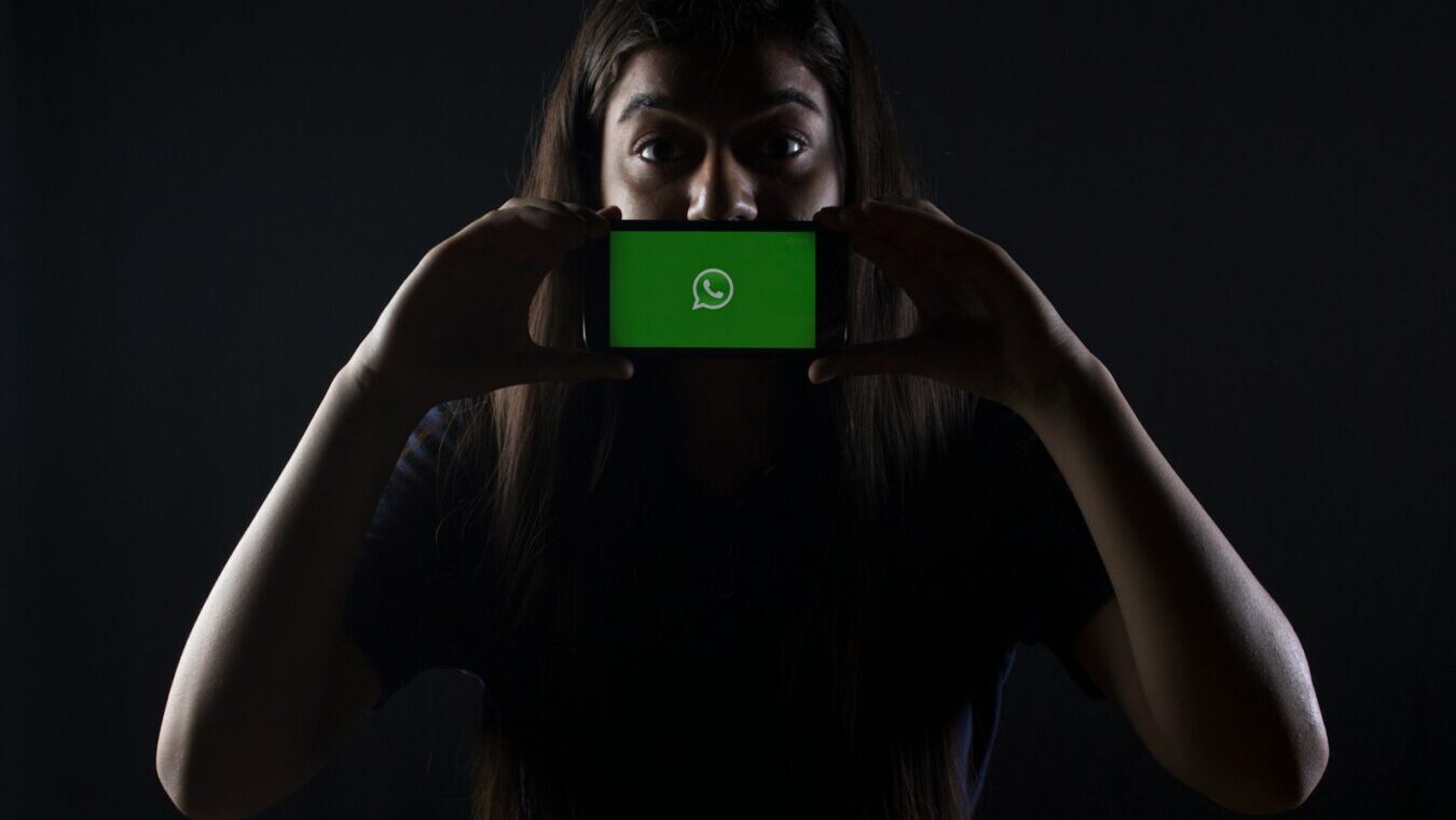 woman holding black smartphone at Whatsapp logo