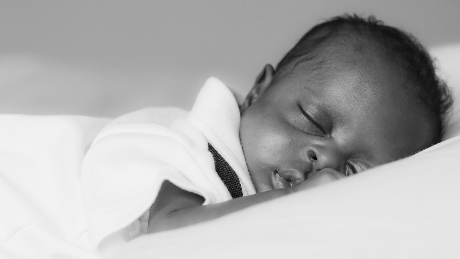 baby in white shirt lying on bed