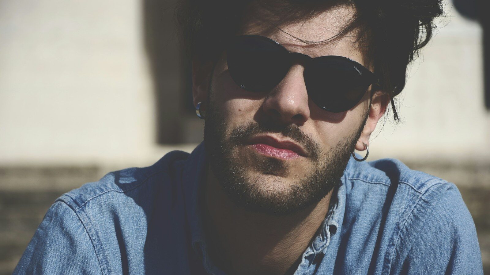 man wearing blue denim top and black sunglasses